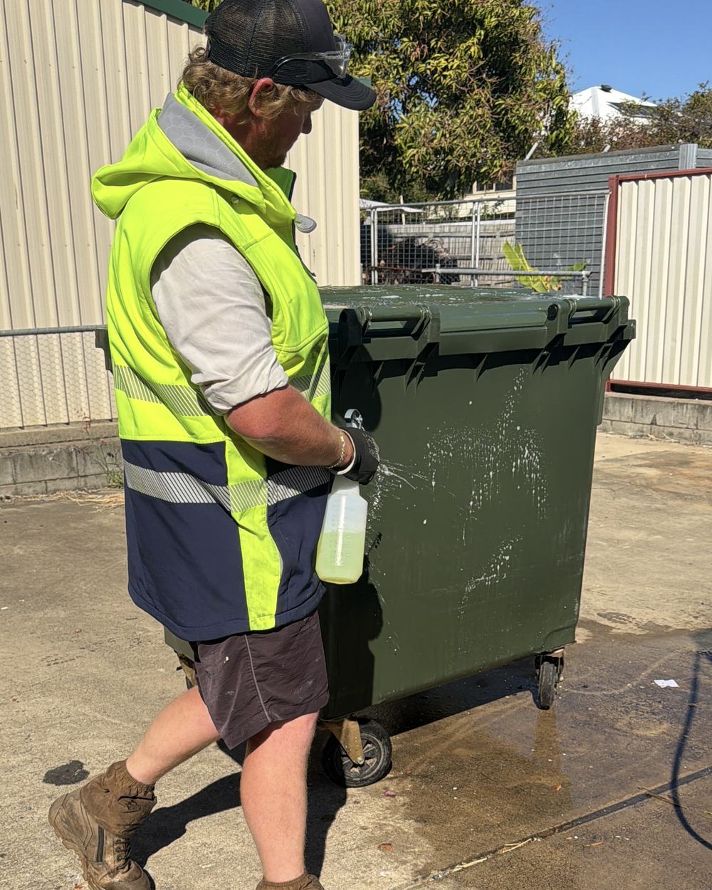 A CQ Bin Cleaners team member cleaning a commercial bin